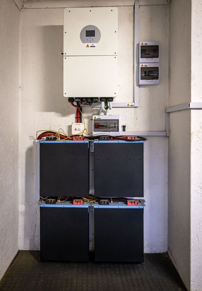 Wandmontierter Wechselrichter mit gestapelten Batteriemodulen im Hausanschlussraum