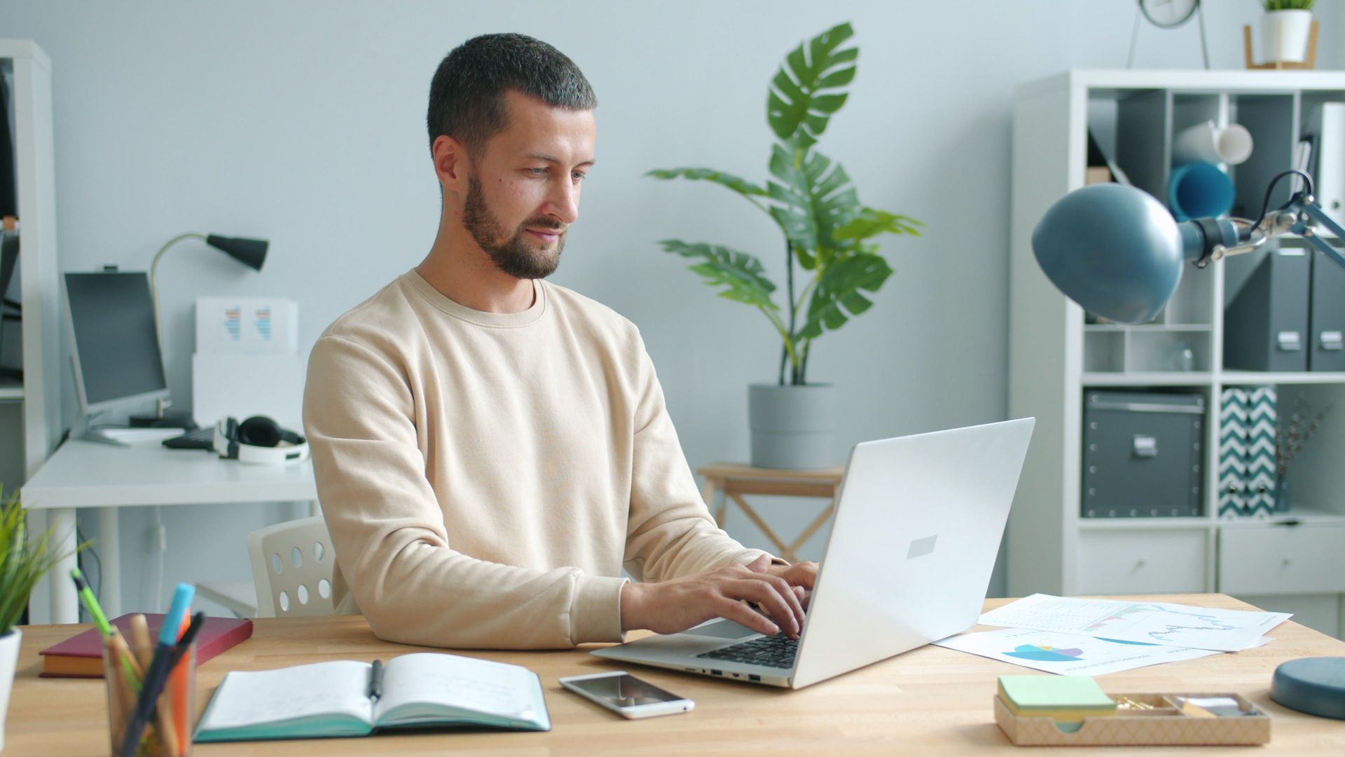 Ein Mann arbeitet konzentriert am Laptop in einem hellen Homeoffice